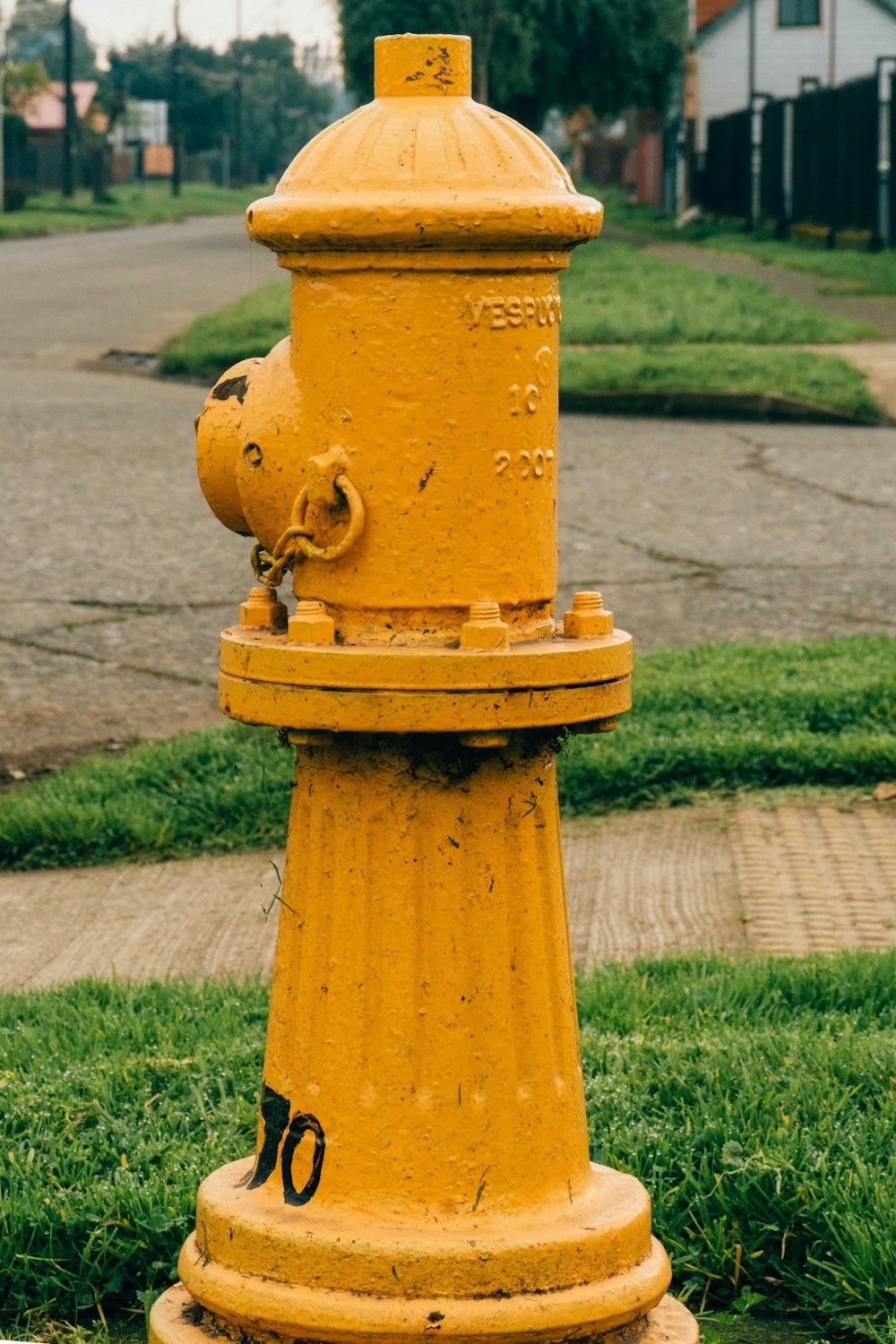 a yellow fire hydrant sitting on the side of a road