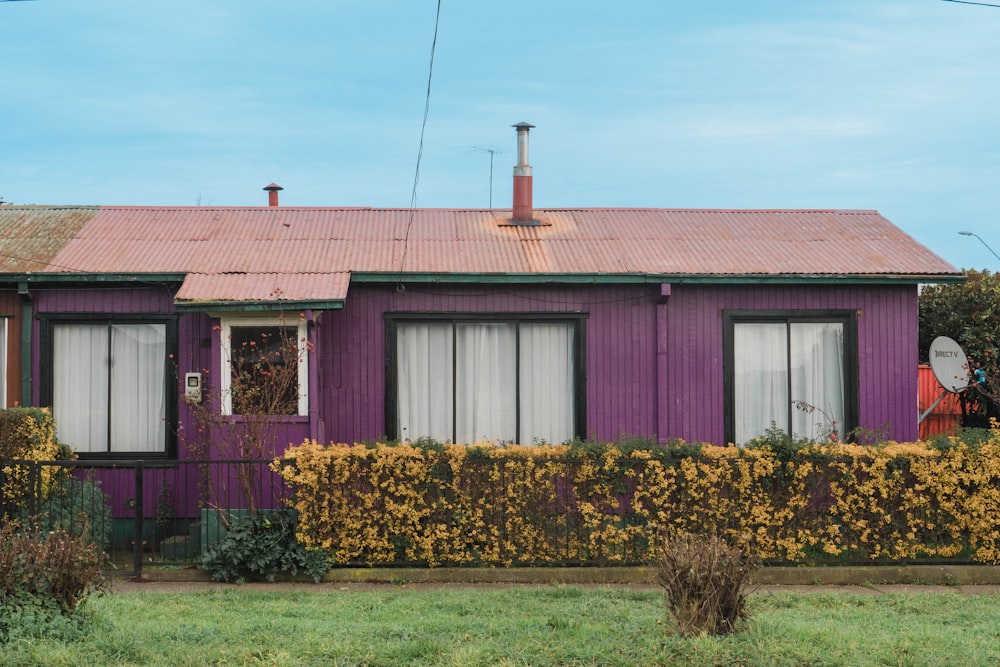 a purple house with a red roof and windows