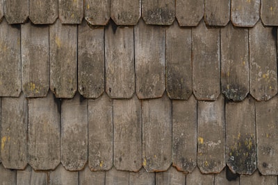 Close-up of hands inspecting a roof’s shingles for wear and tear.
