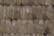 A close-up view of a rustic wooden shingle roof with weathered, overlapping wooden tiles. The surface texture displays signs of aging and wear, with some lichen or moss growth in patches.