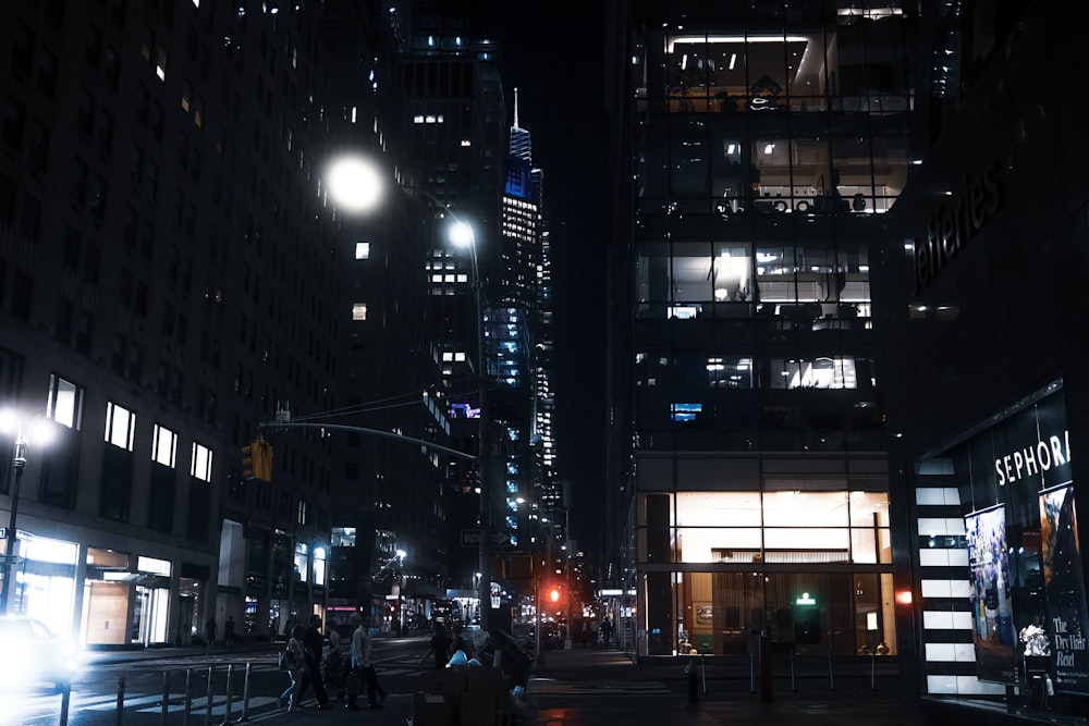 a city street at night with people walking on the sidewalk