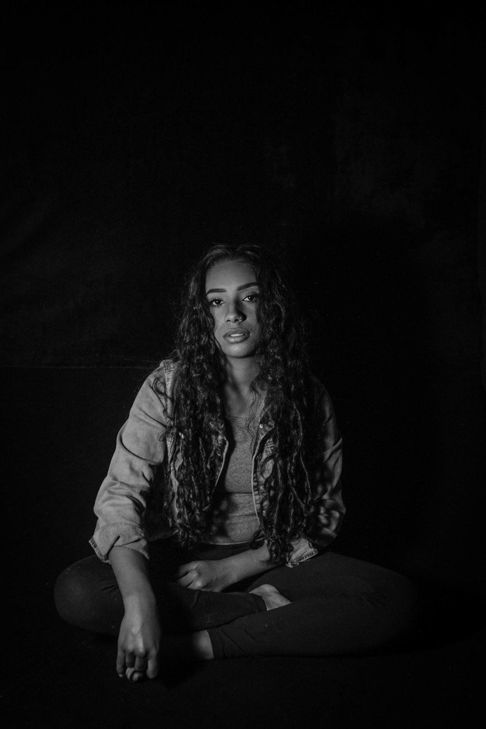 a black and white photo of a woman sitting in the dark