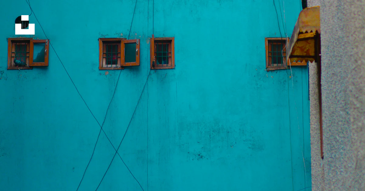 A blue building with several windows and wires photo – Free Windows ...