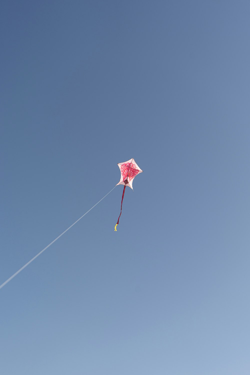 a pink kite flying in a blue sky