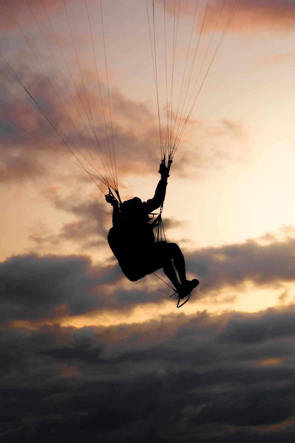 a person is parasailing in the sky at sunset