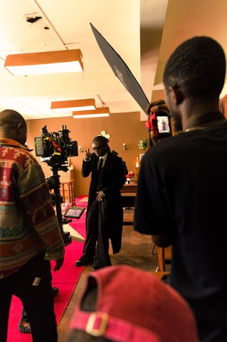A behind-the-scenes shot of a film set with cameras and crew capturing a dramatic scene.