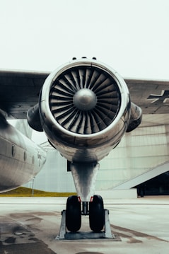 A close-up view of an aircraft engine and landing gear on a concrete surface, showcasing intricate details of the turbine and metallic texture.
