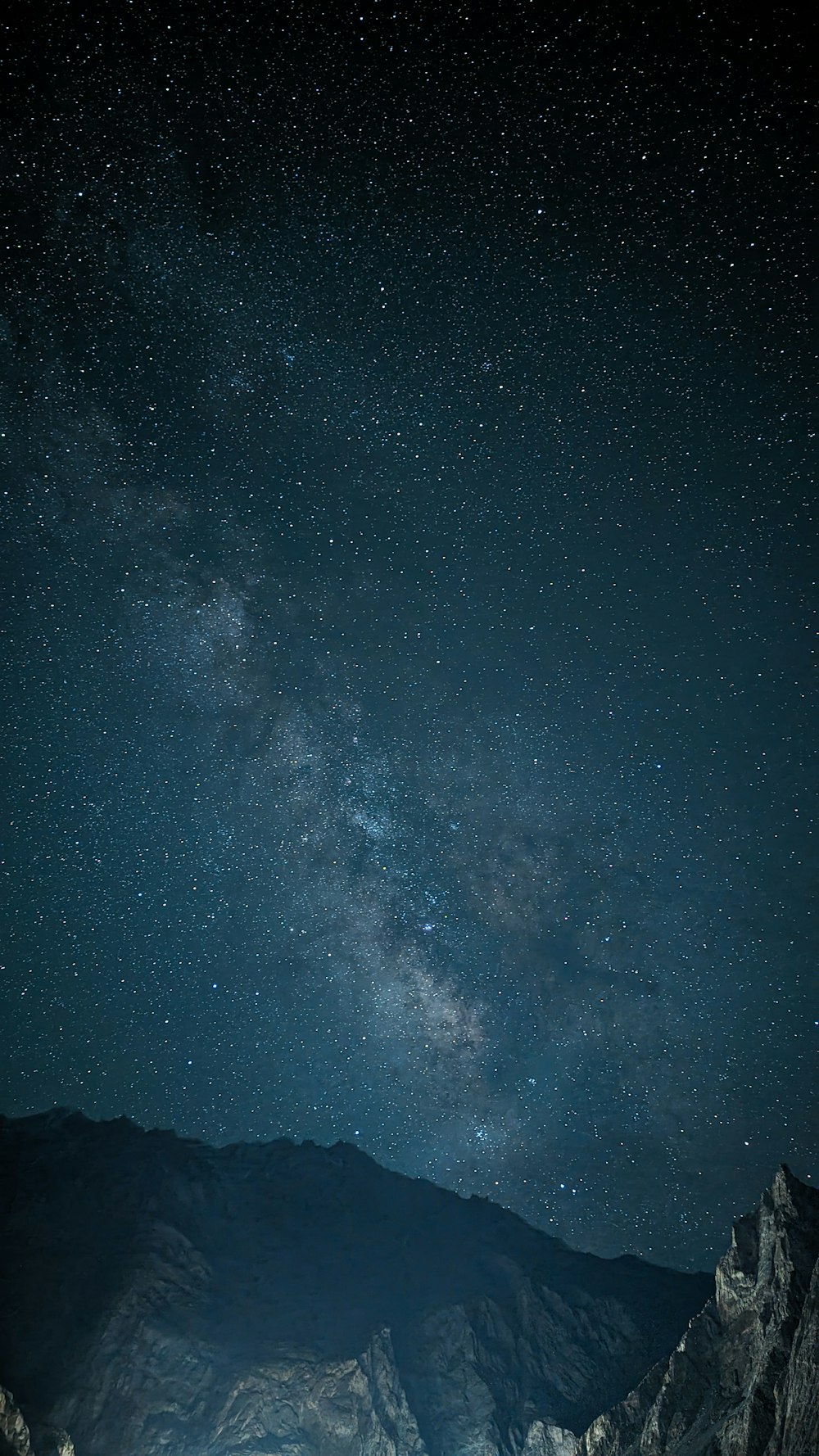 the night sky with stars above a mountain range