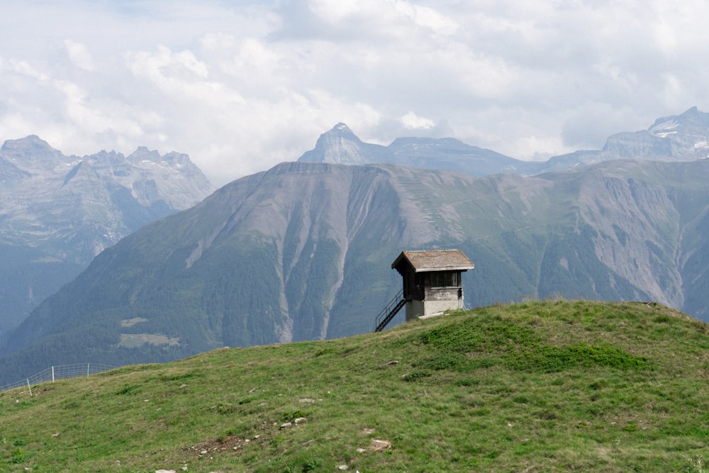 una piccola capanna seduta sulla cima di una collina verde lussureggiante