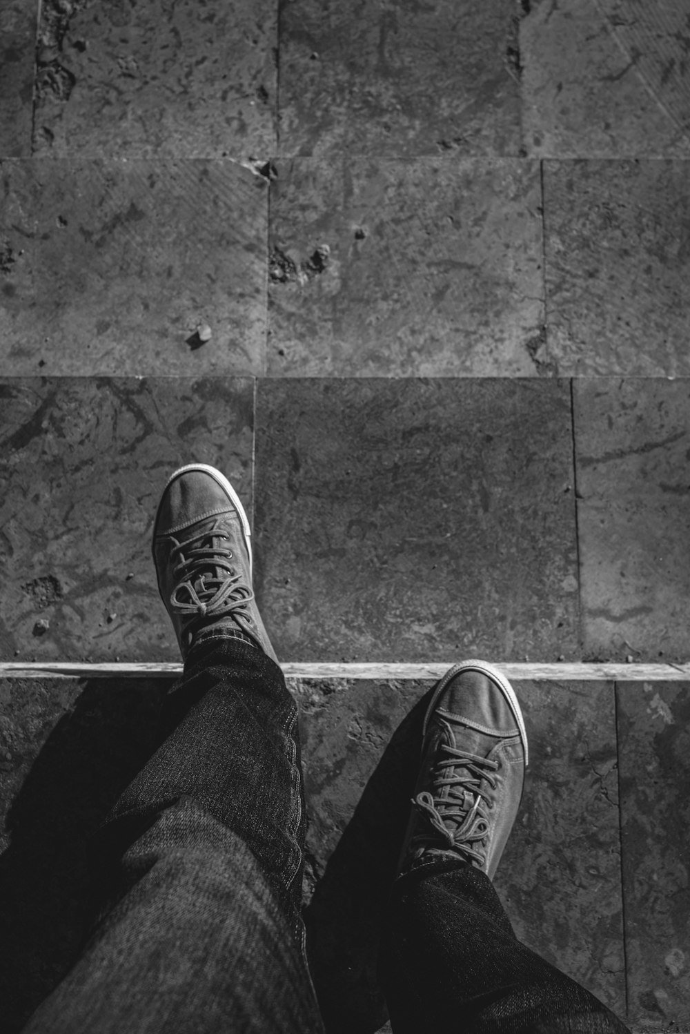 a person's feet in sneakers on a tiled floor