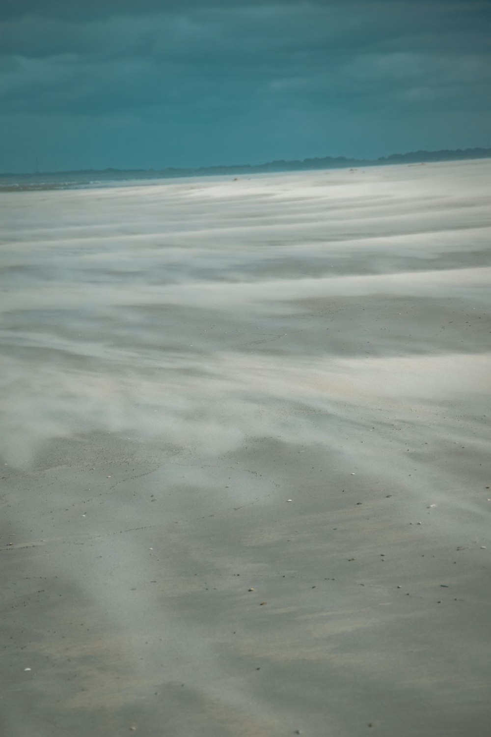 a sandy beach covered in lots of sand under a cloudy sky