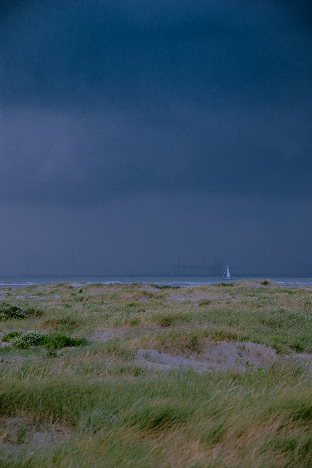 a lone sailboat in the distance on a cloudy day