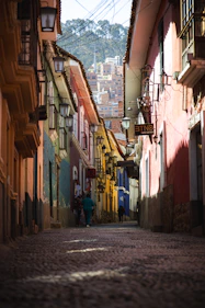 a narrow street with a few people walking down it