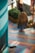 A person wearing a traditional outfit including a bowler hat and a fringed shawl is walking down colorful, painted steps in an urban setting. The walkway features vibrant stripes in blue, orange, pink, and yellow. There are potted green plants lining the path, and graffiti is visible on the surrounding walls.