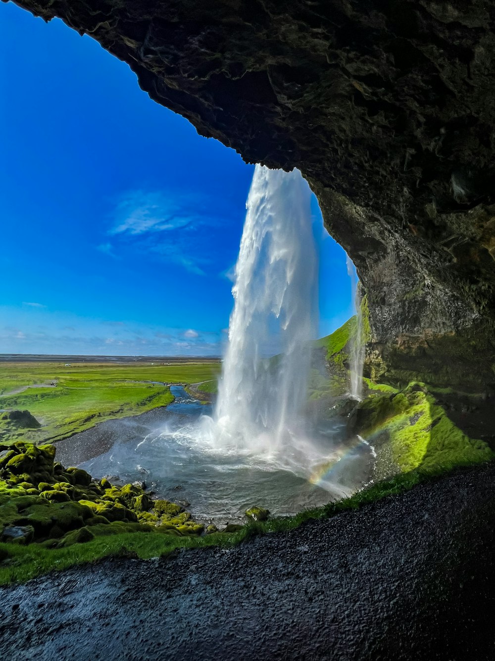 a waterfall is seen from inside a cave