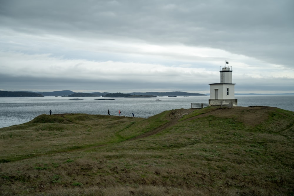 a lighthouse on a grassy hill overlooking the ocean
