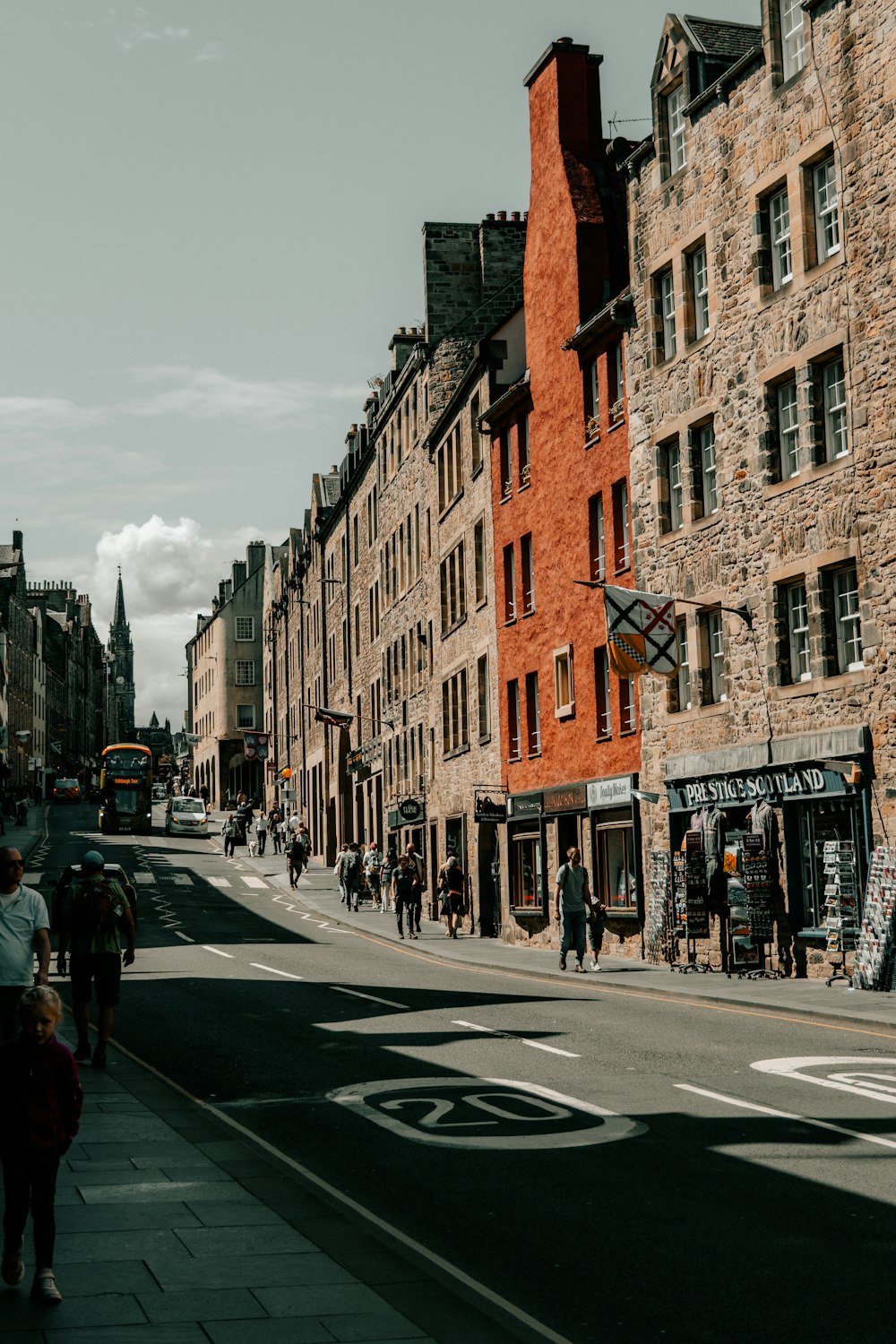 a group of people walking down a street next to tall buildings