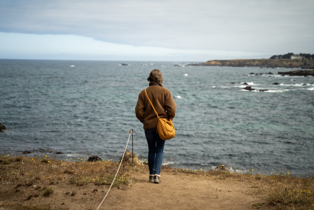 a person walking up a path near the ocean