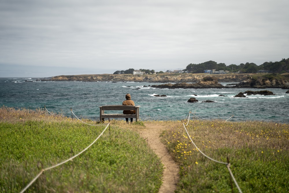 a person sitting on a bench near the ocean