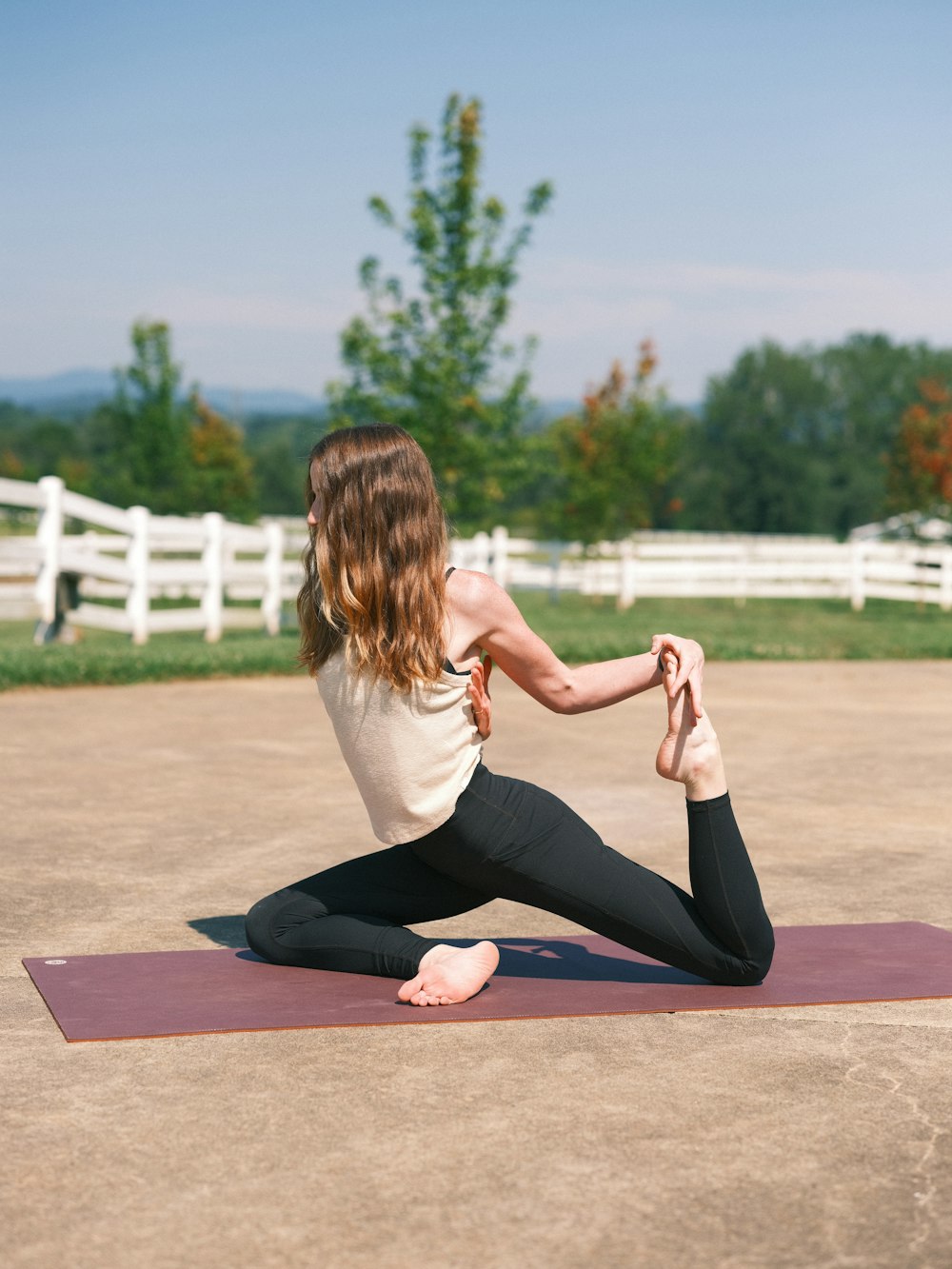 a woman sitting on a yoga mat in a park
