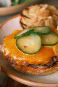 Close-up of a sizzling gourmet burger with melted cheese and fresh toppings on a toasted bun.