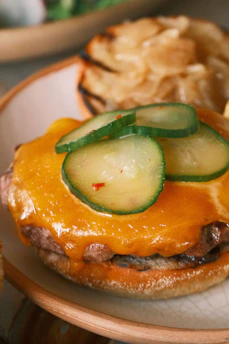 Close-up of a freshly made burger with melted cheese and crispy lettuce on a toasted bun.