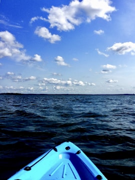 A kayak loaded with fishing gear on a serene blue ocean, under a clear sky.