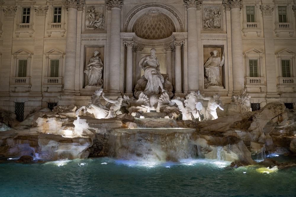 a fountain in front of a building with statues on it