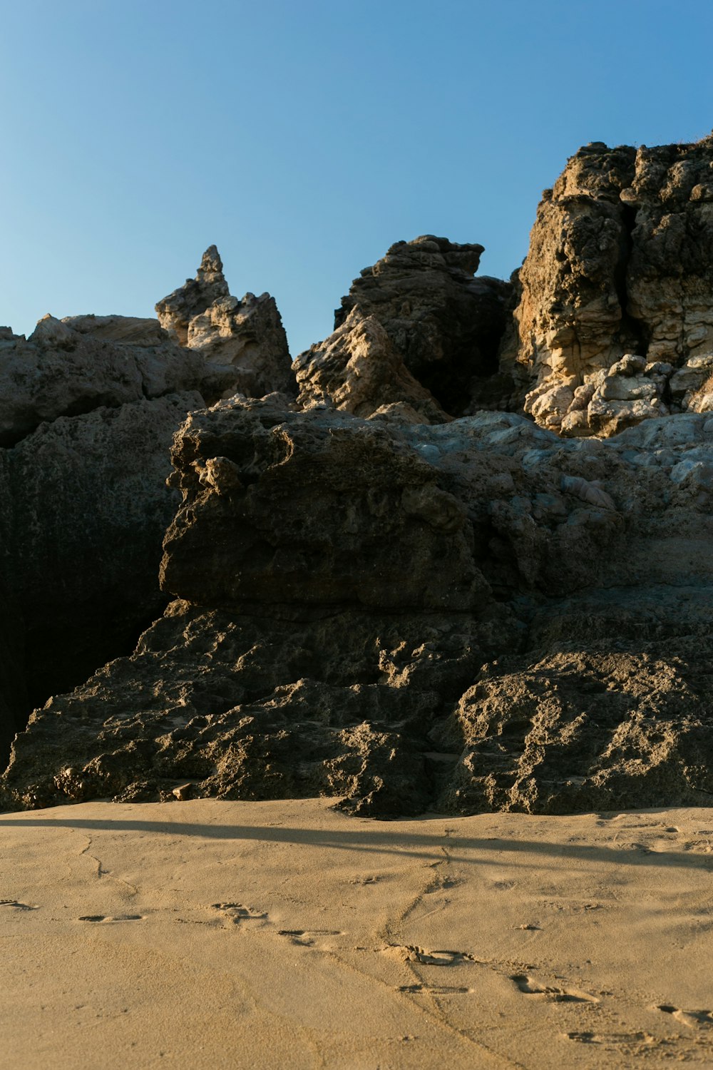 a person walking on a sandy beach next to rocks