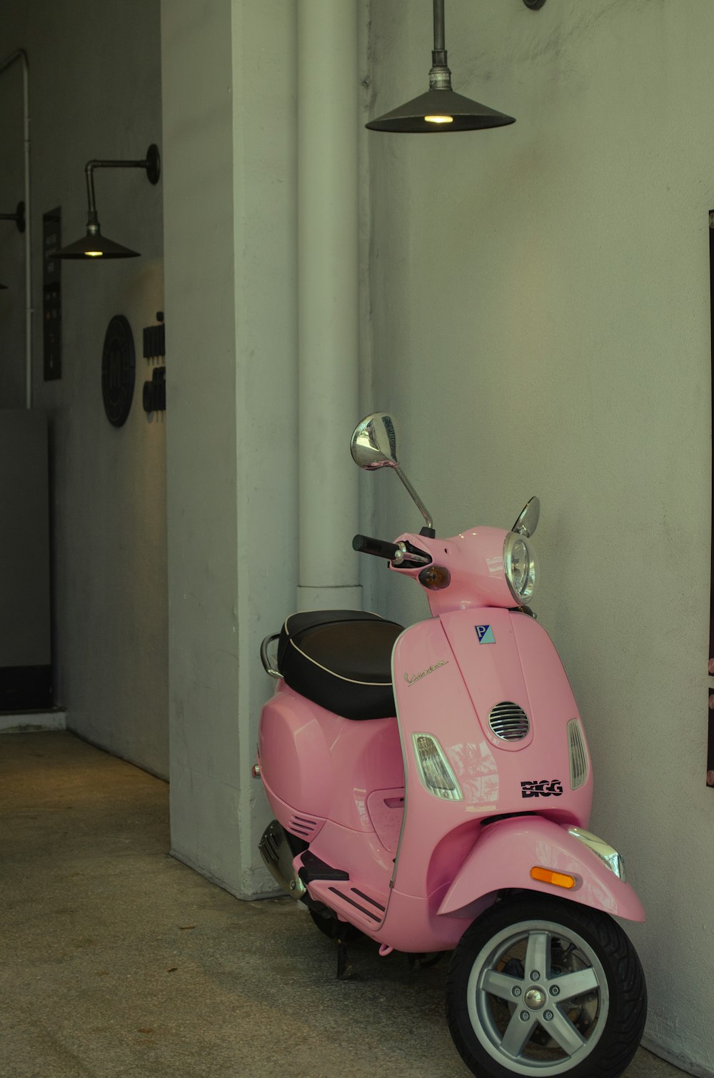 a pink scooter parked next to a white wall
