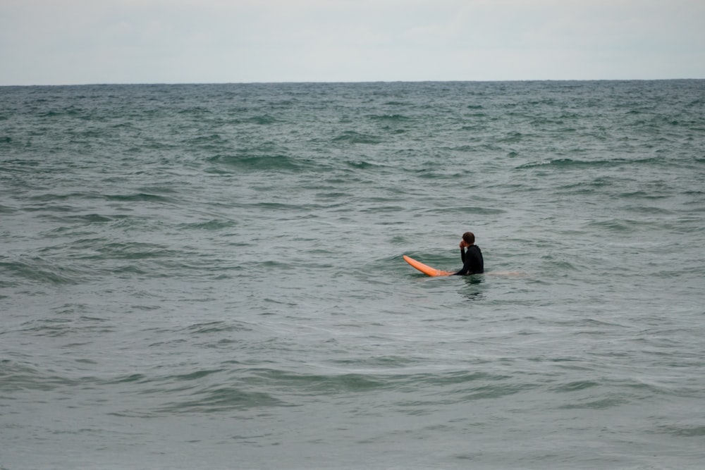 a person sitting on a surfboard in the middle of the ocean