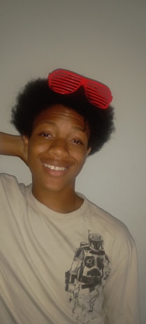 Coach Reynaldo wearing a colorful 1980s workout outfit with a vintage curly wig, smiling confidently.