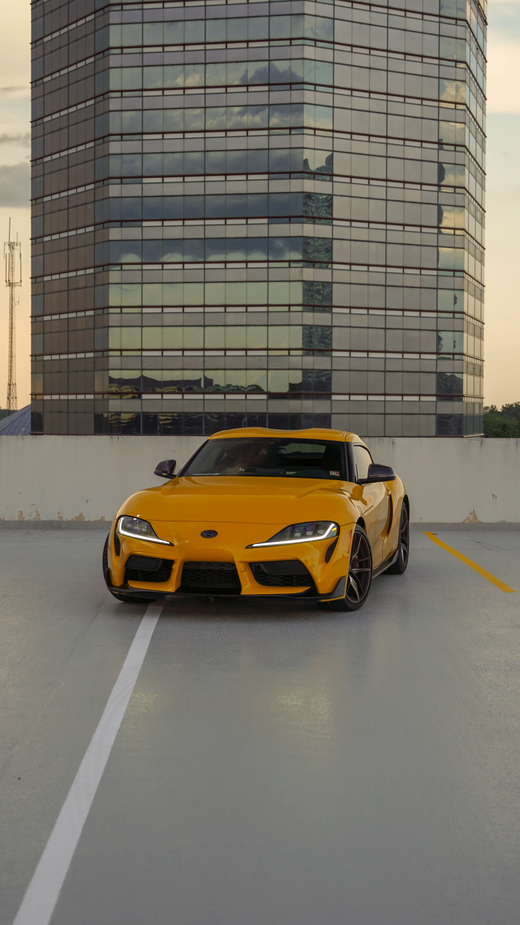Yellow Toyota GR Supra parked in front of a tall building
