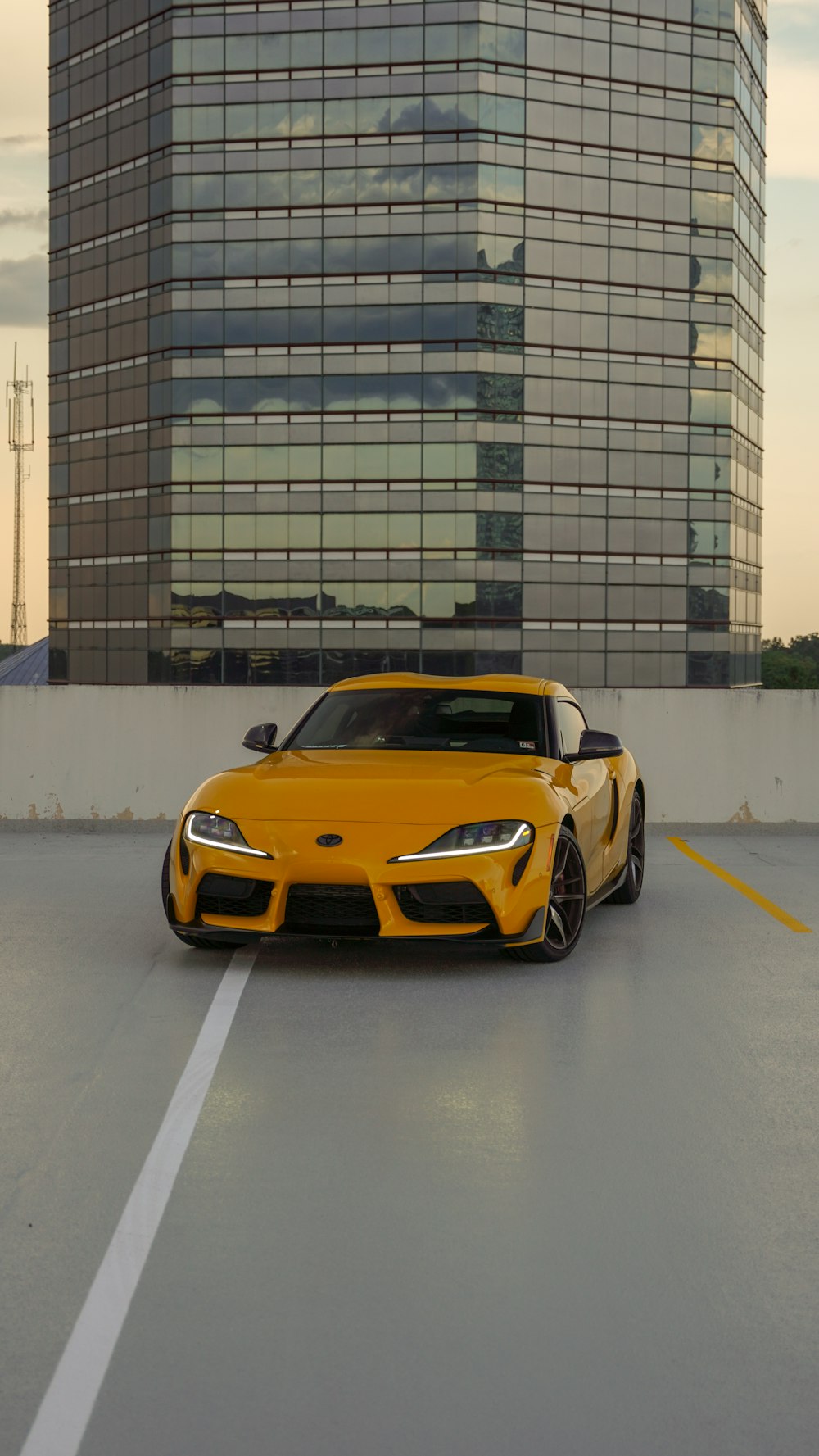 a yellow sports car parked in front of a tall building