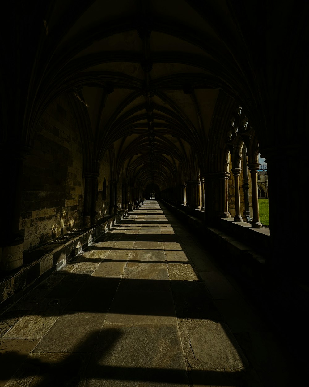 a long hallway with arches and stone flooring