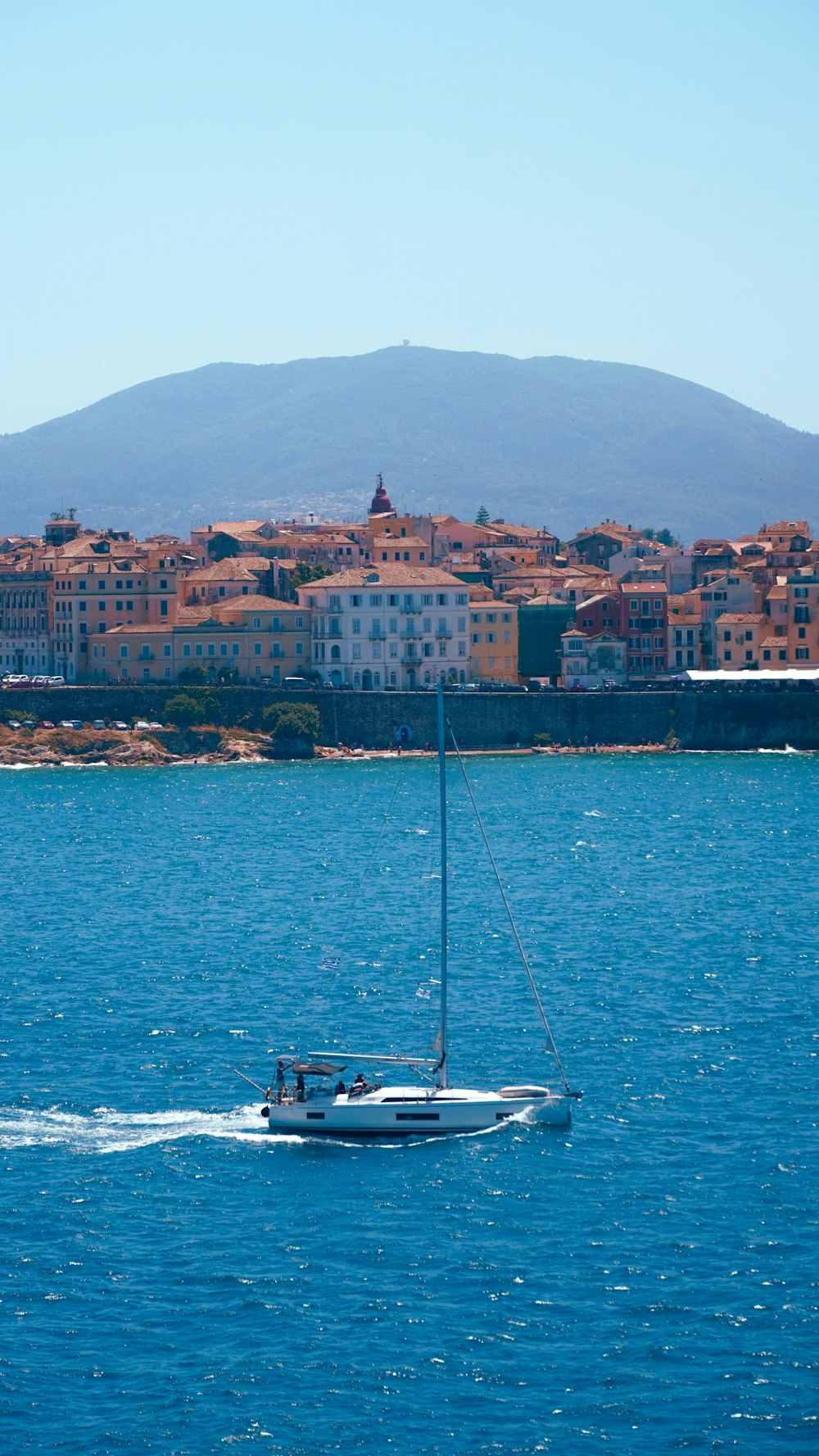 a sailboat in the water with a city in the background