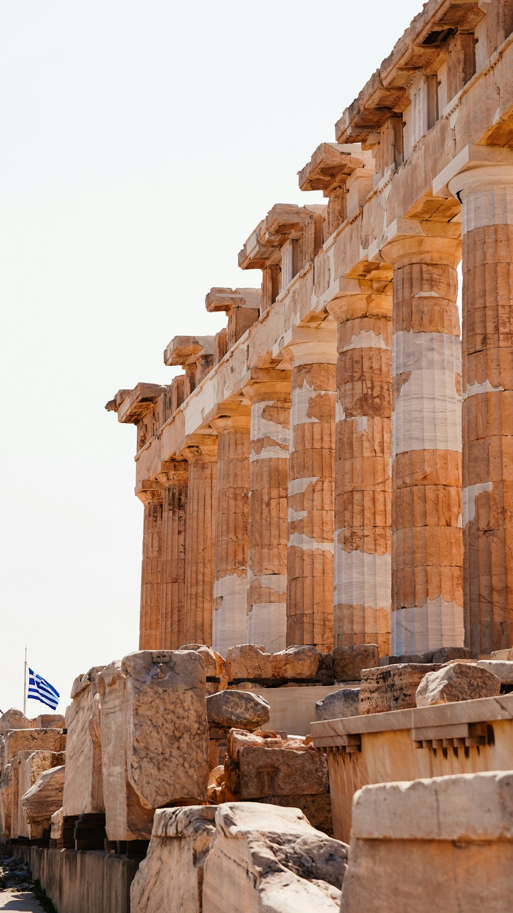 배경에 깃발이 휘날리는 고대 그리스 유적이 줄지어 있습니다