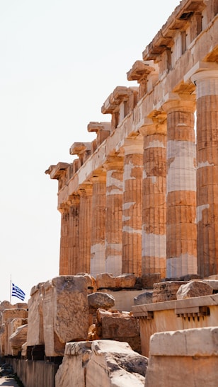 a row of ancient greek ruins with a flag flying in the background