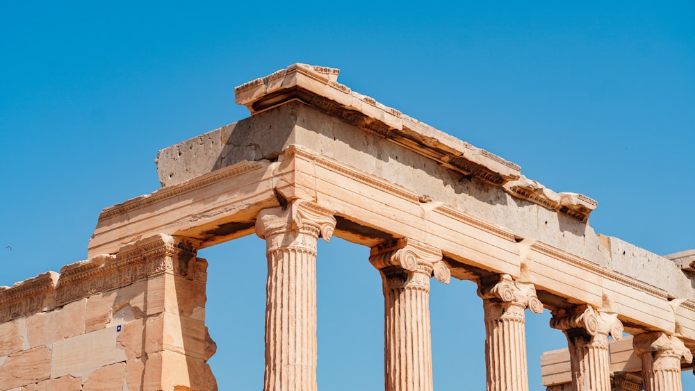 a stone structure with four pillars and a sky background