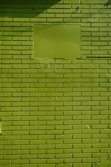 a man riding a skateboard down a street next to a green wall