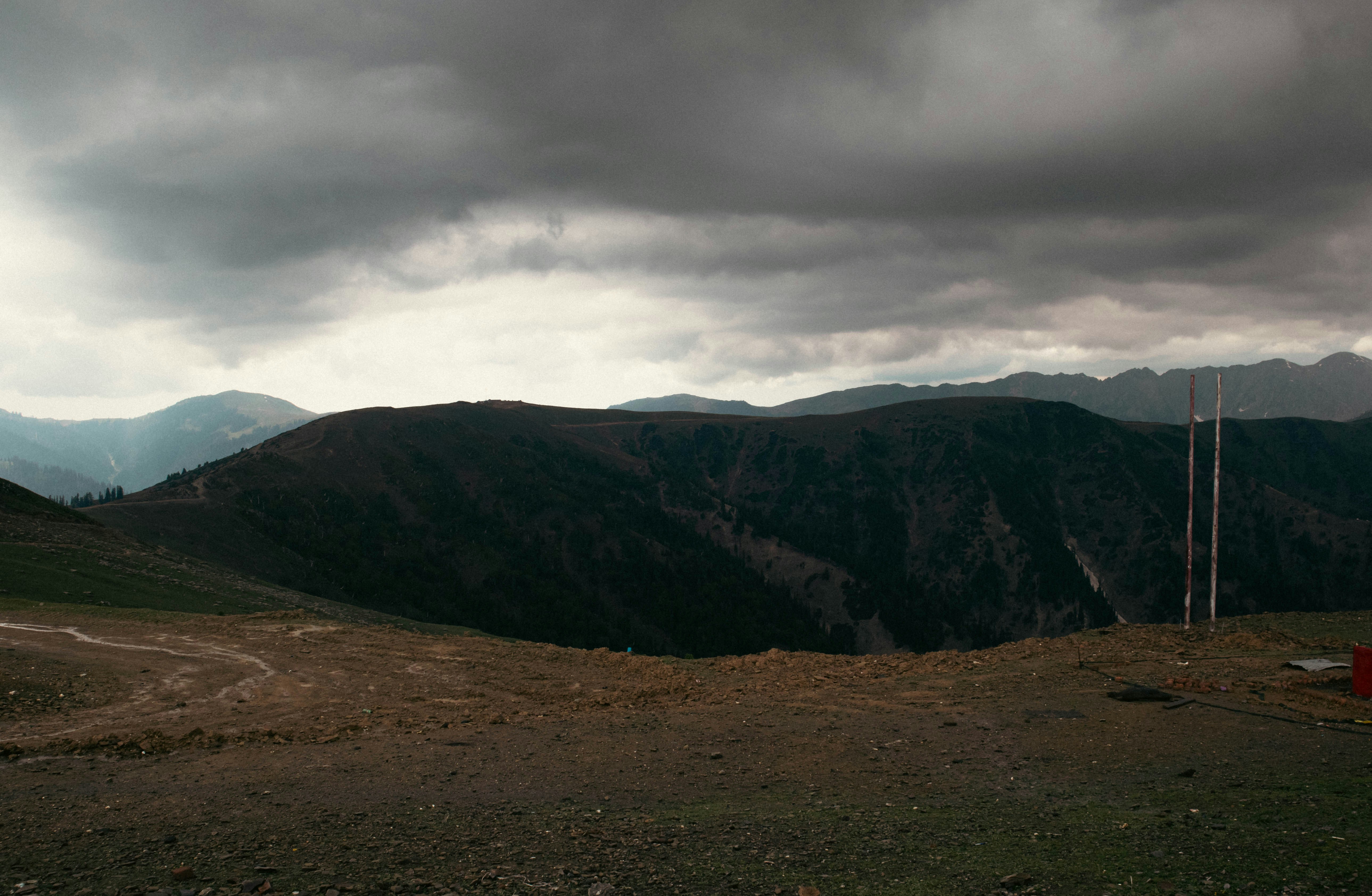 Dramatic high altitude mountain landscape in Central Asia, dark storm clouds, rocky terrain, deeply shadowed valleys