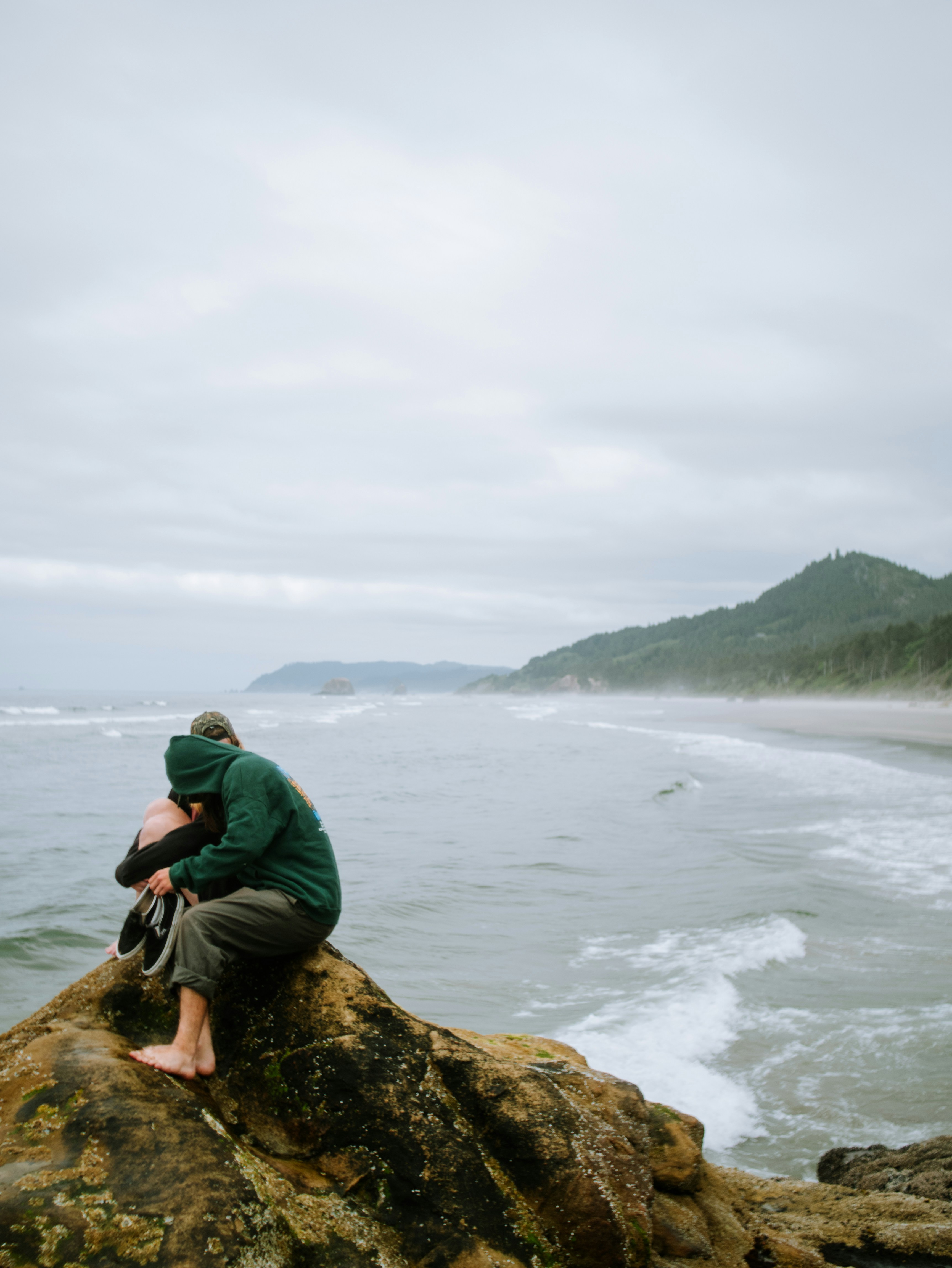 a man sitting on top of a rock near the ocean