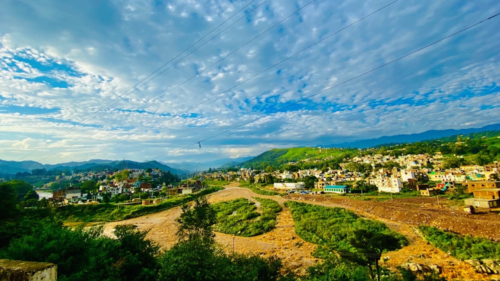 a scenic view of a town and mountains under a cloudy blue sky