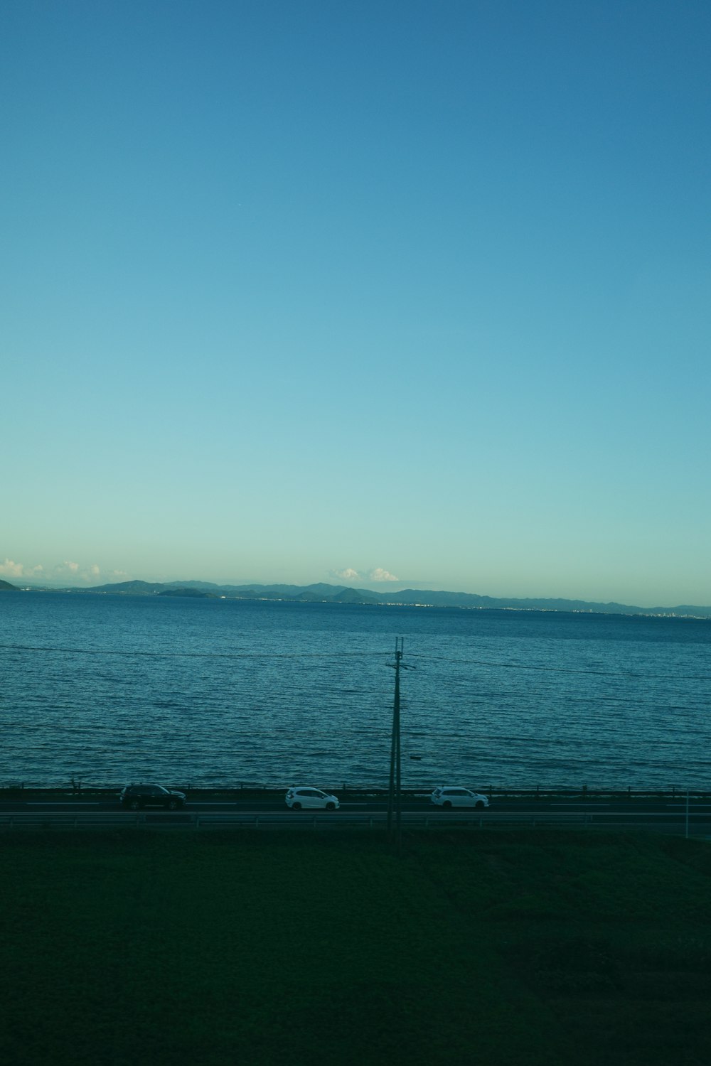 a large body of water sitting next to a lush green field