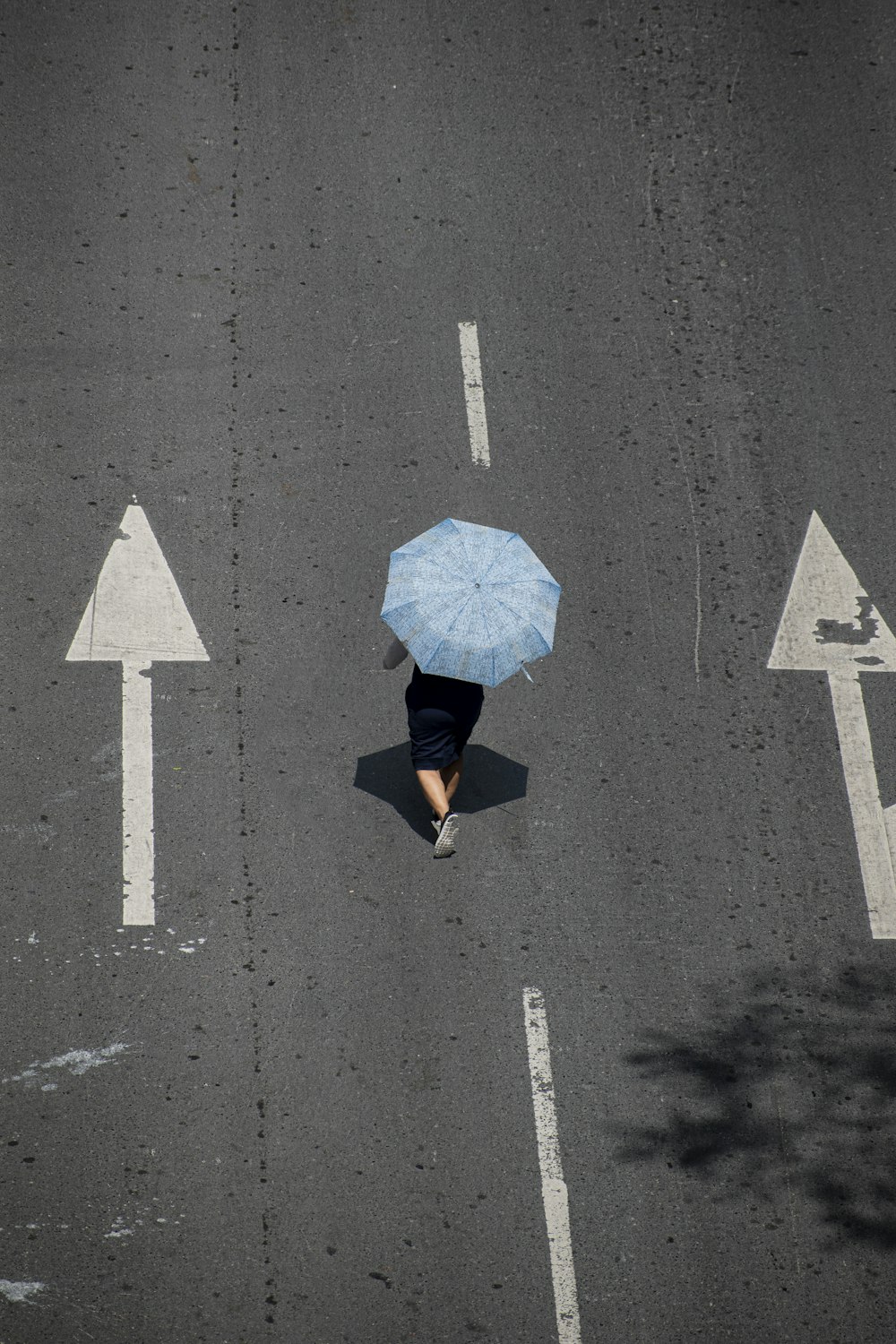 a person walking down a street holding a blue umbrella