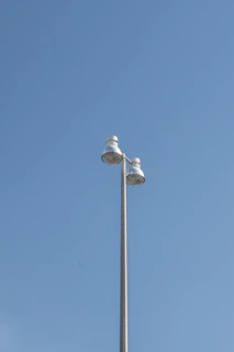 An LED streetlight mounted on a tall pole against a clear blue sky on a sunny day.
