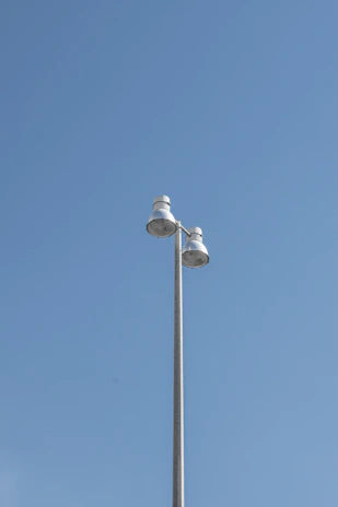 An LED streetlight mounted on a tall pole against a clear blue sky on a sunny day.
