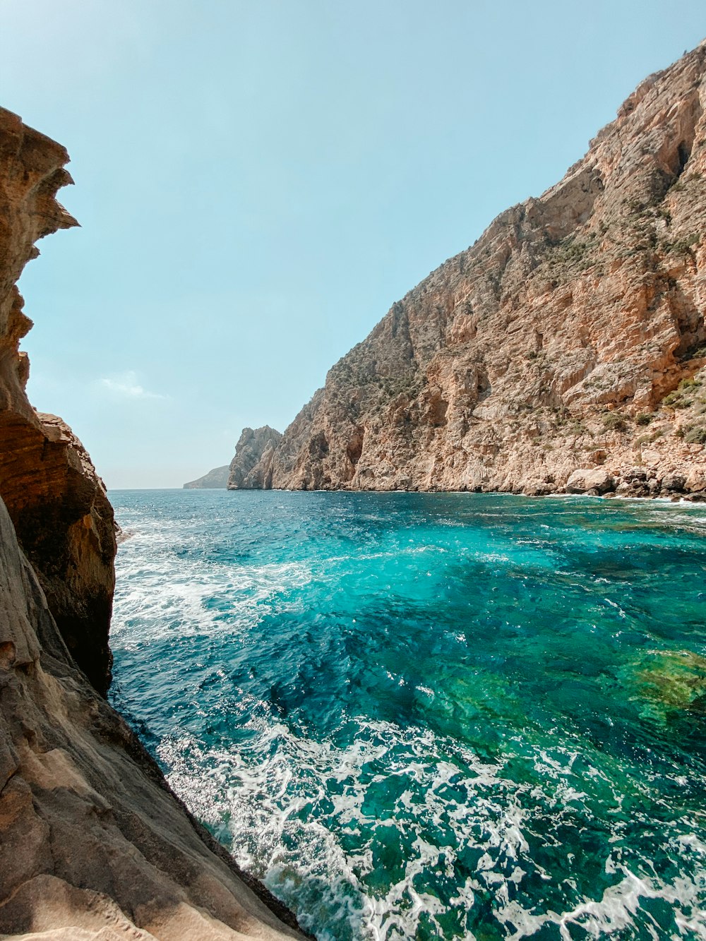 a body of water next to a rocky cliff