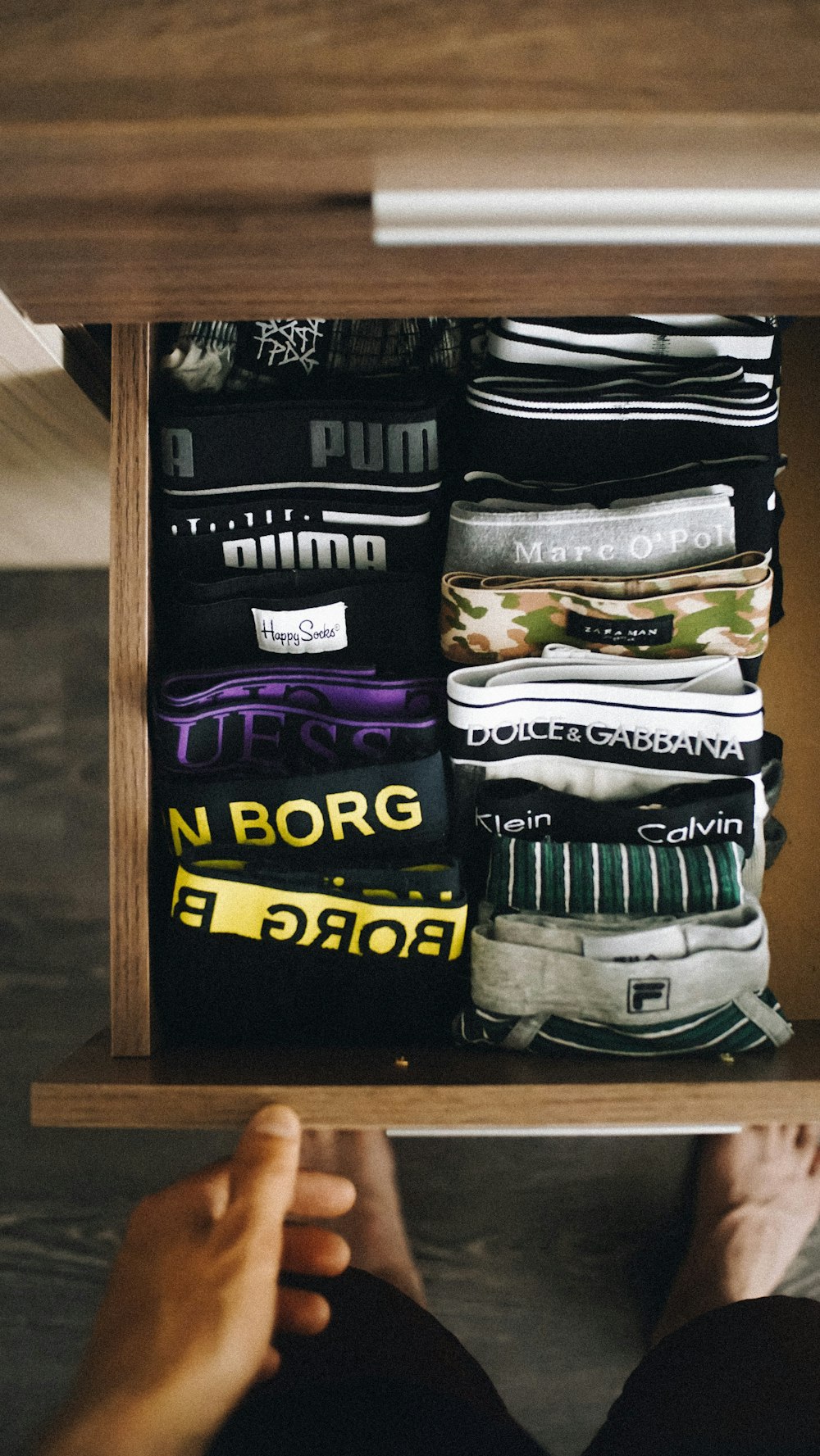 a person's feet resting on a shelf with a drawer full of shirts
