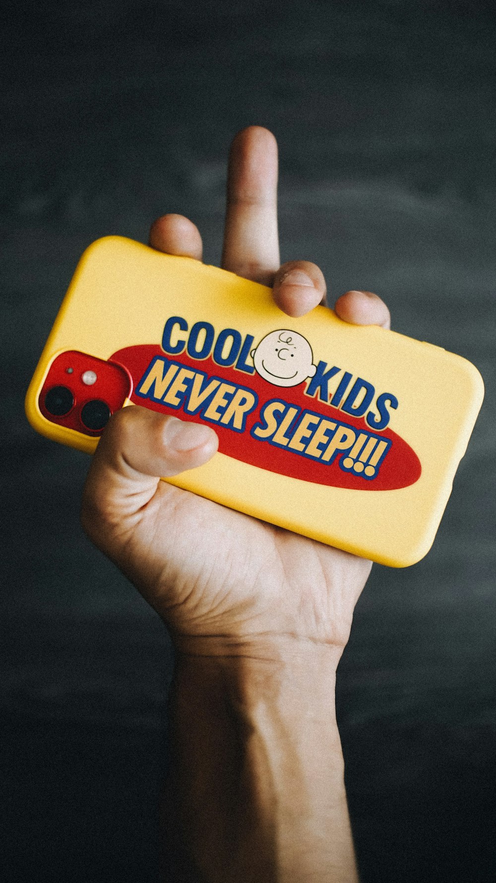 a hand holding a yellow case that says cool kids never sleep